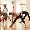 A ChiBall teacher guiding a class holding ChiBalls overhead in triangle pose